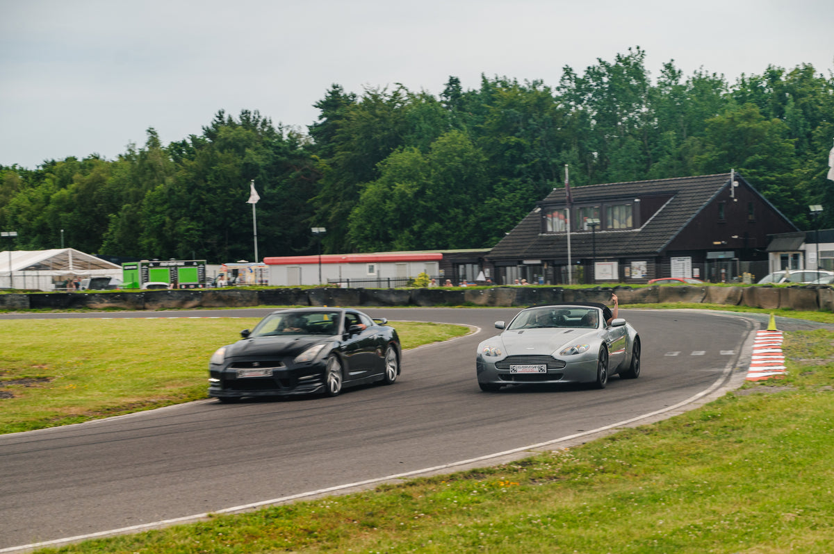 Two sports cars, a black Nissan GT-R and a silver Aston Martin DBS