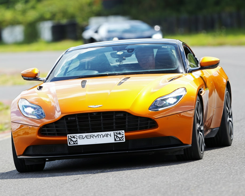 DB11 Orange sports car on a track with blurred background