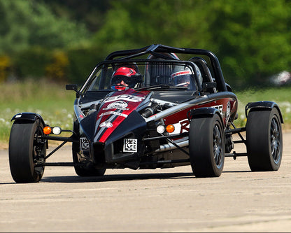 A black Ariel Atom 400R GT with red and white detailing on the body, driving on a track.