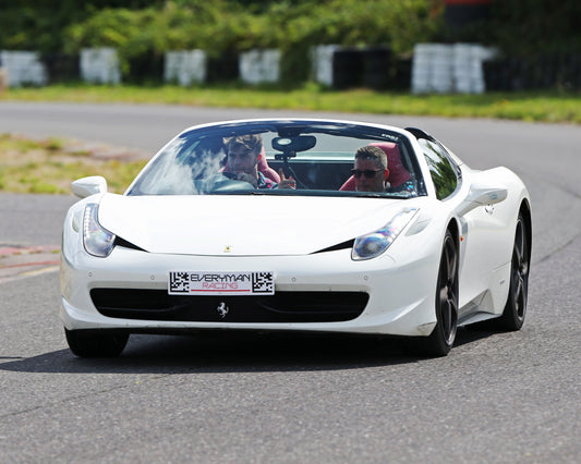 White Ferrari sports car on a track with two people inside