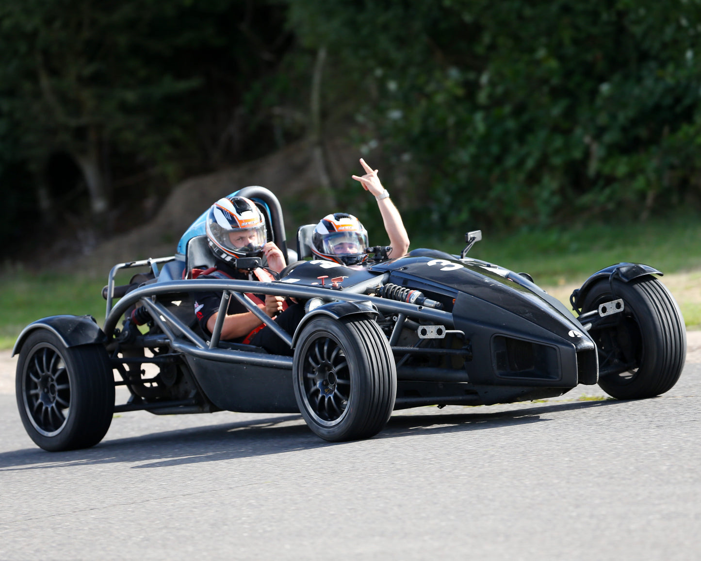Black open-wheeled car on a track with a person waving